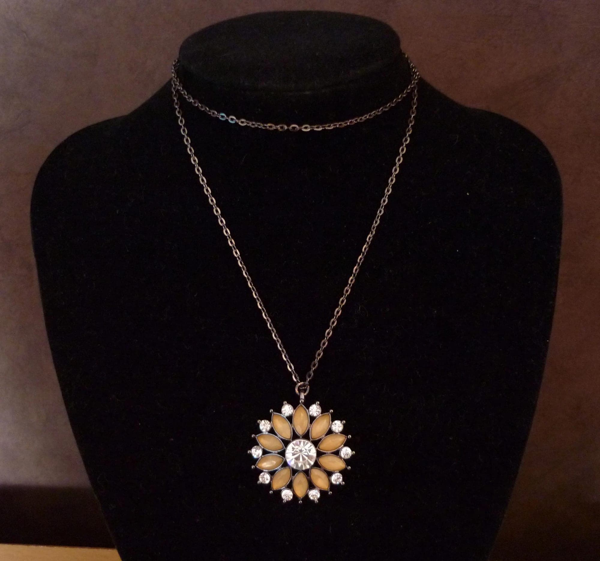 Antracietkleurige ketting met strass bloem hanger met beige stenen