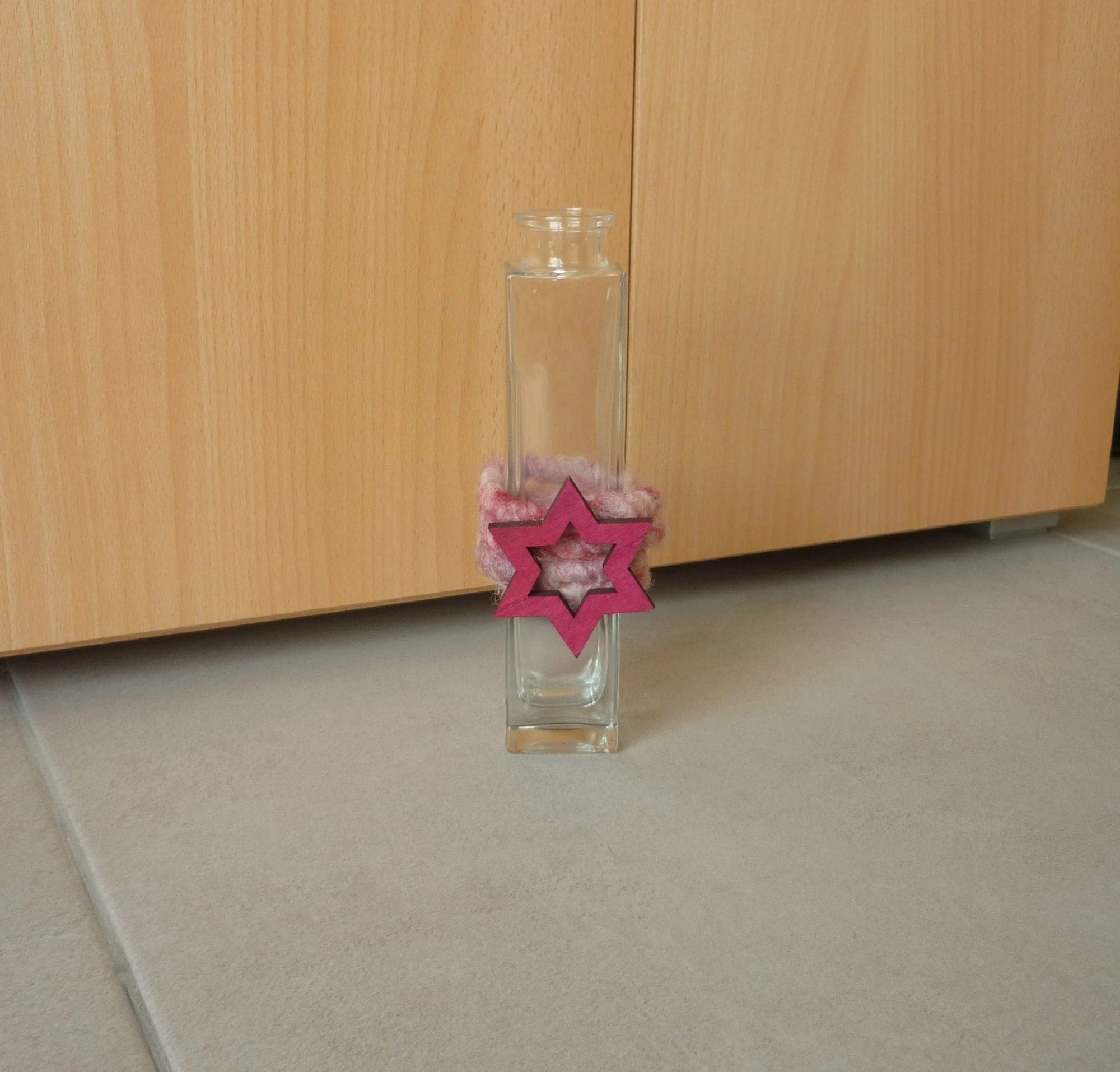 Lange smalle glazen vaas met roze fuchsia touw en ster