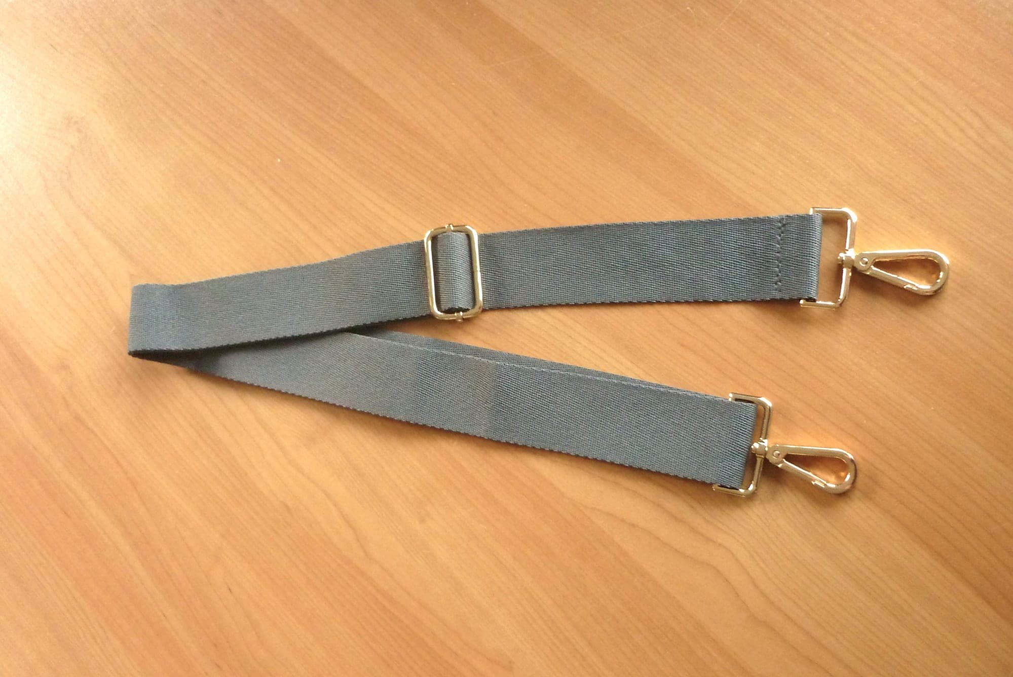 Grijze brede textielen schouderriem schouderband met goudkleurige gespen