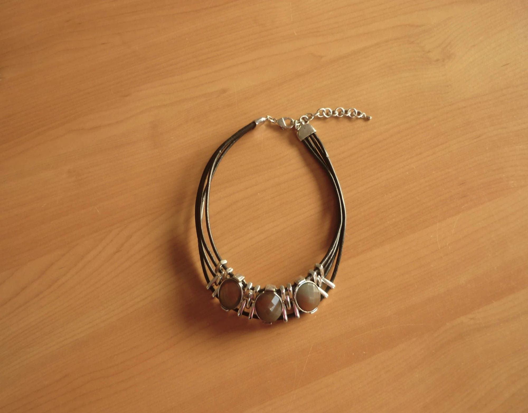 Zwarte vierdubbele choker ketting met zilverkleurige en 3 ovale taupe strass ste