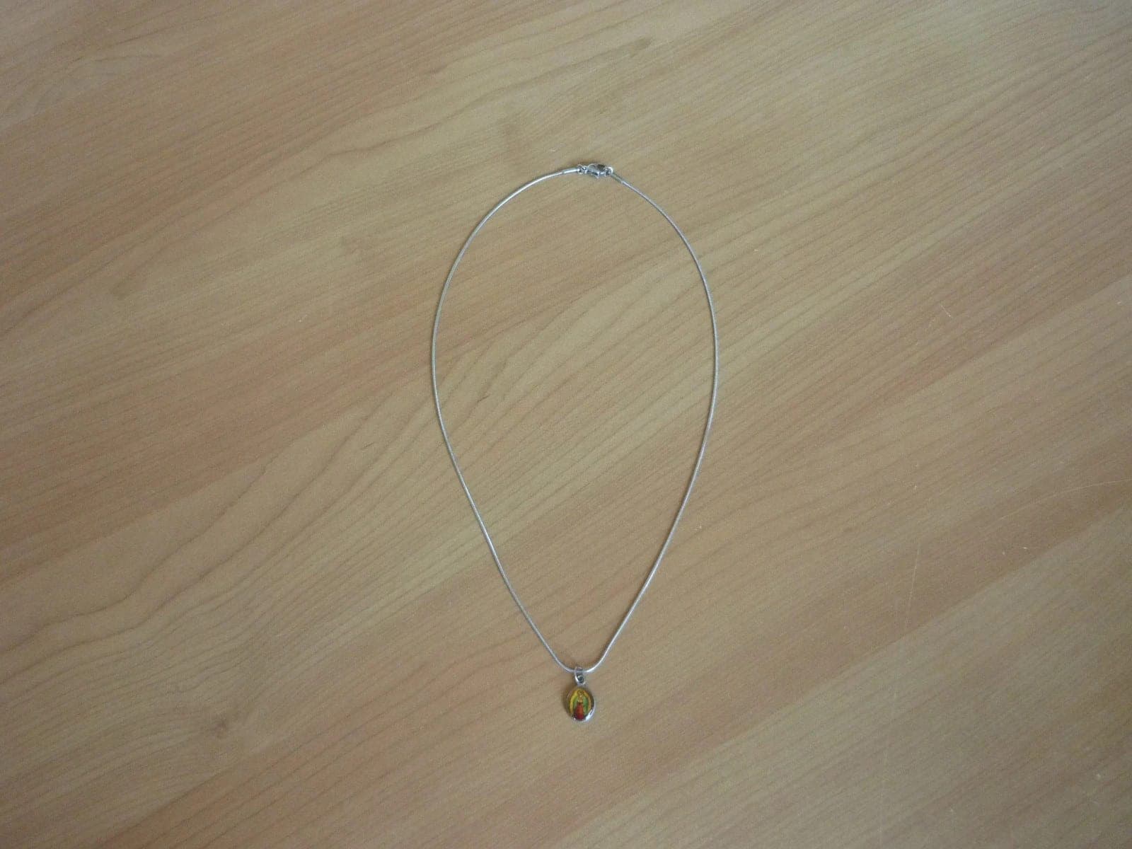 Zilverkleurige ronde ketting met zilverkleurige ovale Mariabeeld en kruis hanger