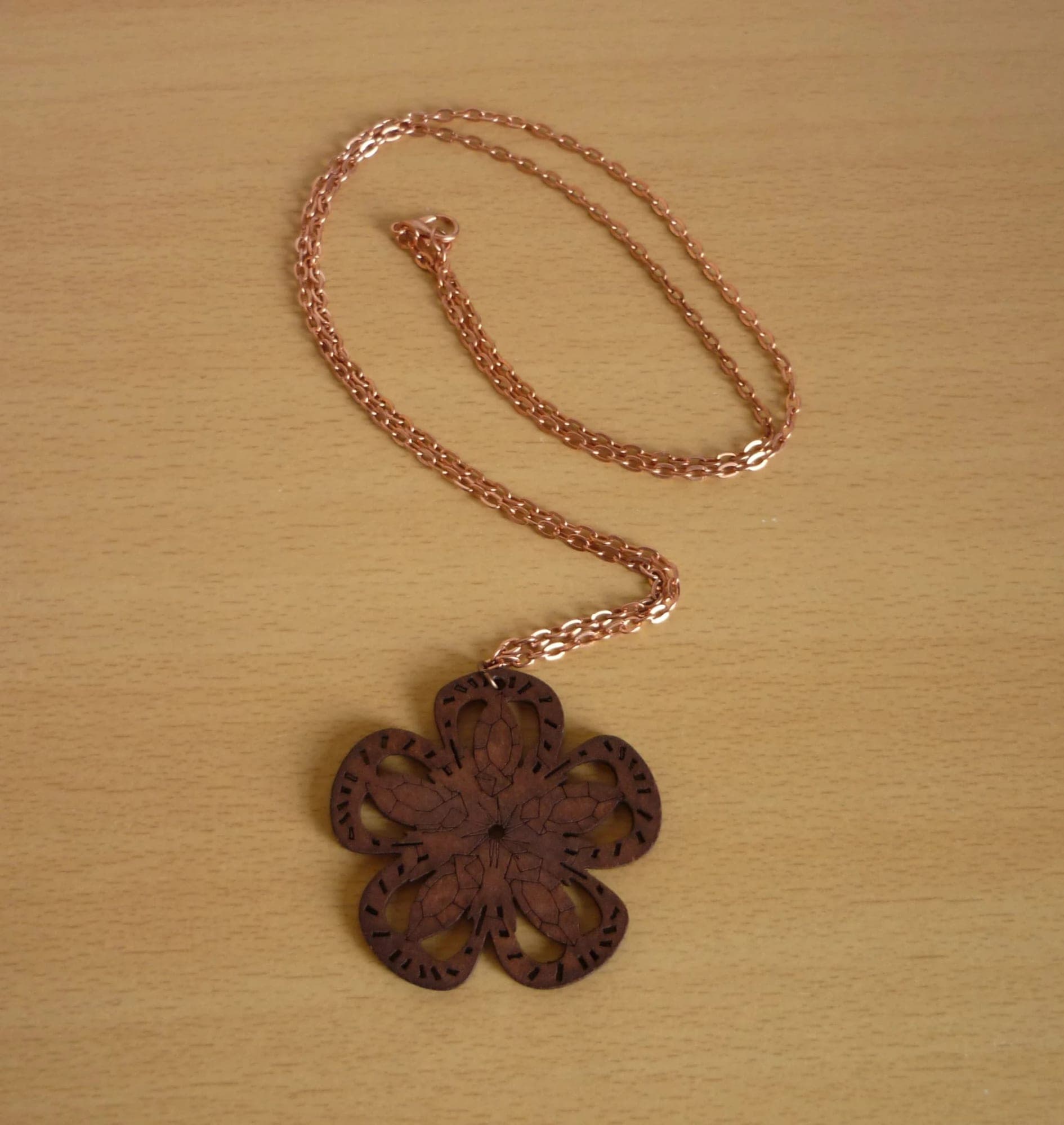 Lange rozegoudkleurige ketting met grote houten bruine bloem hanger