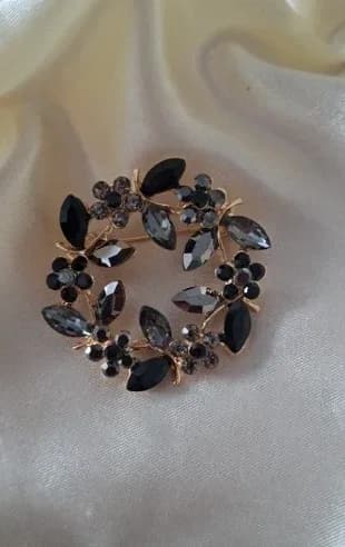 Goudkleurige broche met zwarte en grijze kristallen