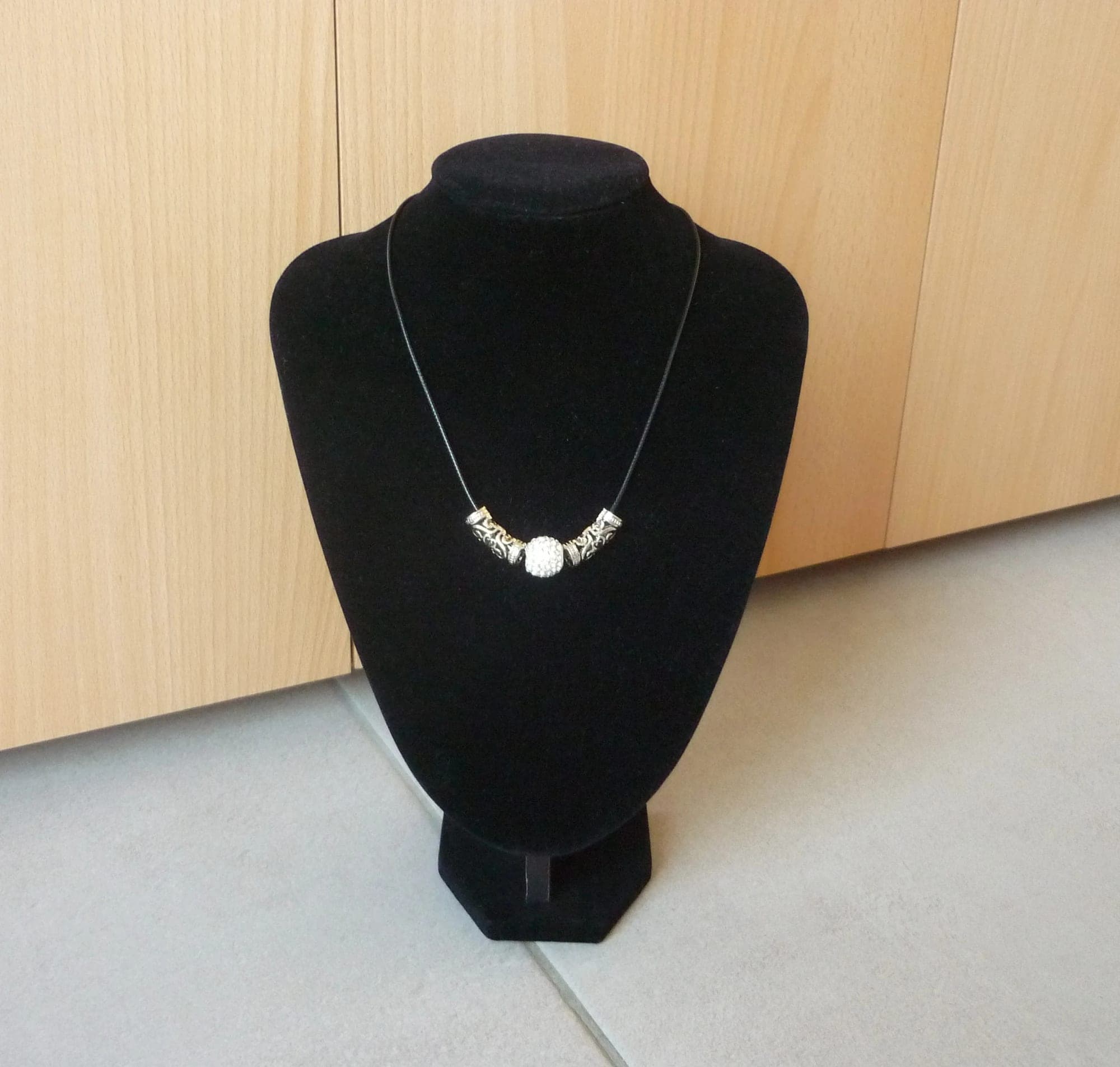 Zwarte touw ketting met witte strass bol hanger en zilverkleurige kokers